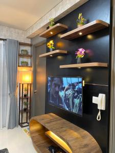 a living room with a tv on a black wall at Batam Three Bedrooms Apartment - One Residence 2AG - in Batam Center