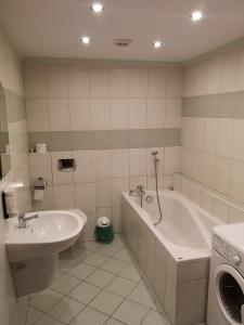 a bathroom with a tub and a sink and a washing machine at Pokoje Gościnne Gdańska 21 J in Świnoujście
