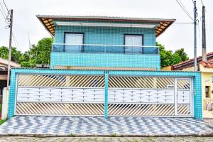una casa azul con una puerta frente a un edificio en Casa com Wi-Fi a 400 metros da Praia Maracanã-SP en Solemar