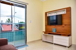 Casa com Wi-Fi a 400 metros da Praia Maracanã-SP في Solemar: غرفة معيشة مع تلفزيون ونافذة كبيرة