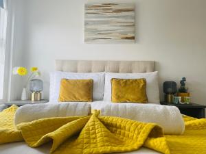 a bedroom with a bed with yellow blankets and pillows at Westcliffe Apartments in Southport