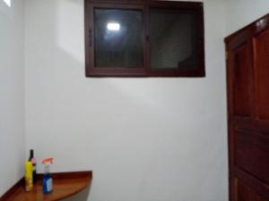 uma janela numa parede branca com uma prateleira de madeira em Casa Hotel Familiar 
