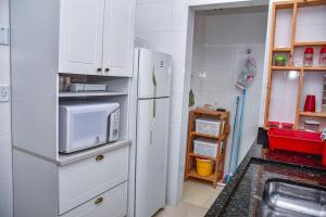 Casa com Wi-Fi a 400 metros da Praia Maracanã-SP في Solemar: مطبخ مع ثلاجة وميكروويف