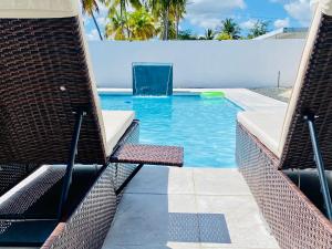 - une piscine avec 2 chaises dans un complexe dans l'établissement Whole Apartment/Private Pool/Netflix/Wifi, à Carolina