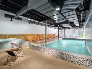 a swimming pool in a building with chairs around it at Pinia Hotel & Resort in Špindlerův Mlýn