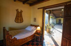 een slaapkamer met een bed en een tafel met een lamp bij Hotel Museo Mayan Inn in Chichicastenango