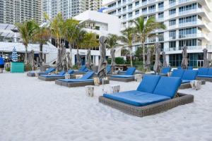 a sandy beach with blue lounge chairs and palm trees at Stunning Condo 2/2 At Hyde BeachResort Beach Front in Hollywood