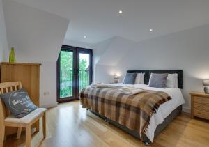 a bedroom with a bed and a chair and a window at Tai Marian Group Cottages in Llangadwaladr