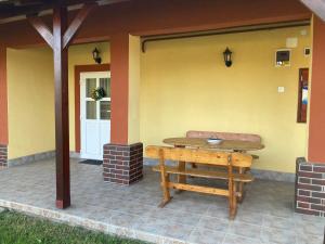 a patio with a wooden table and a bench at Tiszavirág Vendégház in Tiszacsege