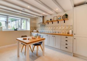 cocina con armarios blancos y mesa de madera en Stabal Bodran, en Llanfair Talhaiarn