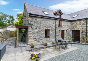 a stone cottage with a patio and a table at Tai Marian Group Cottages in Llangadwaladr