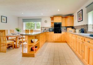 a large kitchen with wooden cabinets and a table at Swn y Nant in Dinorwic