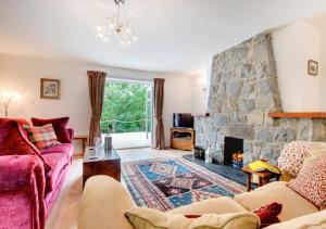 a living room with a fireplace and a stone wall at Swn y Nant in Dinorwic