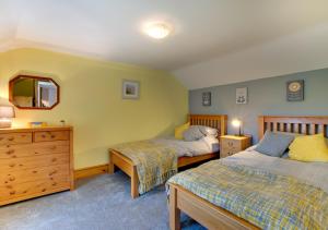 a bedroom with two beds and a dresser and a mirror at Top Y Nant in Mold