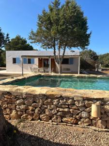 una casa con una pared de piedra alrededor de una piscina en Casa Mayo, en Sant Francesc Xavier