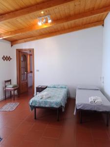 two beds in a room with a wooden ceiling at Casa vacanza Ligustro appartamento il toro in SantʼAntìoco