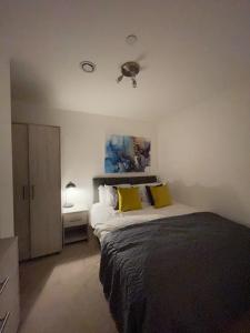 a bedroom with a large bed with yellow pillows at 1-Bedroom Apartments in the Heart of Central Woking in Woking