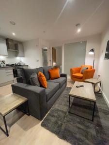 uma sala de estar com um sofá cinzento e uma cadeira laranja em 1-Bedroom Apartments in the Heart of Central Woking em Woking