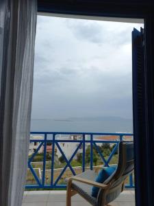una finestra con vista sull'oceano e una sedia di La casa azul a Megalochori (Isola di Agistri)