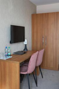 a room with a desk with a television and pink chairs at M&W Hotel Wronowski in Łomża
