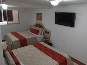 a hotel room with two beds and a flat screen tv at Hotel Zulita in Bogotá