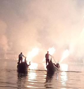 drei Männer auf Gondeln im Wasser mit Feuer in der Unterkunft Giudecca Palanca 664 in Venedig