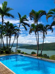 a swimming pool with palm trees and a view of a lake at Mirante do Lago in Capitólio