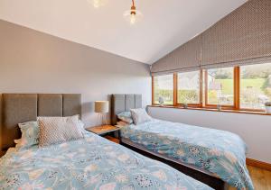a bedroom with two beds and a window at Ysgubor y Graig in Halkyn