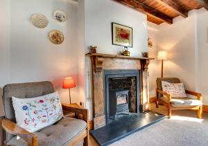a living room with a fireplace and two chairs at West End Cottage in Llangennith