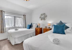 a bedroom with two beds with blue pillows and a window at Valley Rise By My Getaways Free Parking in Portslade