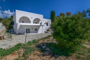 un bâtiment blanc avec un arbre devant lui dans l'établissement Eva House Dryos Beach Paros, à Drios