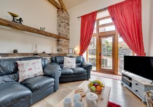 a living room with leather couches and a tv at Ysgubor y Berwyn in Llanarmon Dyffryn-Ceiriog