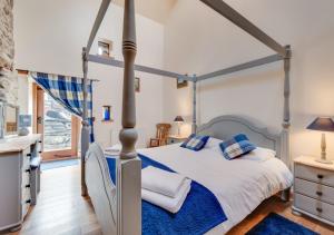 a bedroom with a canopy bed with blue and white sheets at Ysgubor y Berwyn in Llanarmon Dyffryn-Ceiriog