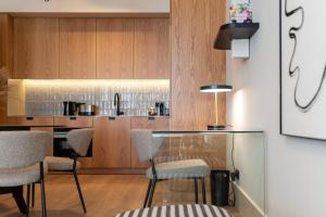 una cocina con armarios de madera y un bar con sillas en Ando Living - Santa Catarina Townhouse, en Oporto