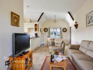 een woonkamer met een bank en een tv en een keuken bij Frome Lodge House in Dorchester