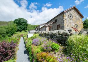 ein Steinhaus mit Garten davor in der Unterkunft Ystabl y Berwyn in Llanarmon Dyffryn-Ceiriog