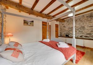 a bedroom with a white bed in a room with a stone wall at Ystabl y Berwyn in Llanarmon Dyffryn-Ceiriog