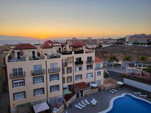 a building with a pool in front of a sunset at Apartment next to Ajabo Beach Pool & Ocean view in Callao Salvaje