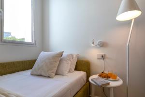 een kleine kamer met een bed met een tafel en een lamp bij The Fetch - Residenze Esclusive sull'Acqua in Alghero