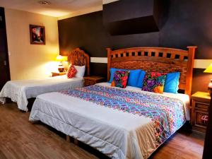 a bedroom with two beds with colorful pillows at Hotel Chocolate Tradicional in Guanajuato