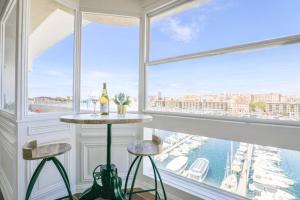 une chambre avec une table et deux tabourets devant une fenêtre dans l'établissement Vieux-Port - Vue exceptionnelle - 3 ch et clim, à Marseille