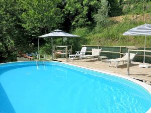 une grande piscine bleue avec 2 chaises et un parasol dans l'établissement Charming Le Pole in Vallico Sopra, à Bolognana