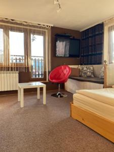 ティリチにあるWilla Abaの赤い椅子とベッドが備わるホテルルームです。