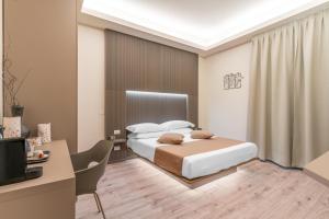 um quarto com uma cama, uma secretária e uma televisão em Meneghina Suites Foresteria Lombarda em Milão