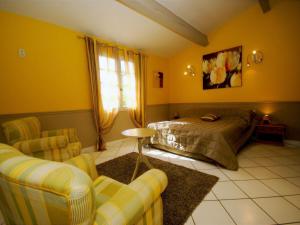 a bedroom with yellow walls and a bed and chairs at Modern Holiday Home in Le Thor with a Pool in Le Thor