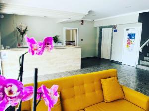 a yellow couch in a room with pink flowers at Hotel Susuqui in Sanxenxo