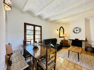 een woonkamer met een tafel en een klok aan de muur bij La Paliane in Calonge