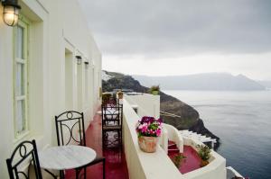 balcone con tavoli, sedie e vista sull'oceano di Angel Cave Houses a Oia