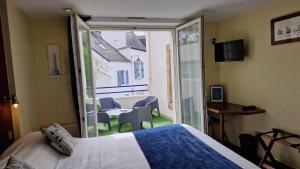 sypialnia z łóżkiem oraz balkon ze stołem i krzesłami w obiekcie Hotel Le Marin w mieście Auray