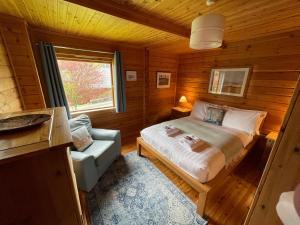 a bedroom with a bed and a chair in a cabin at Luxury 3 bedroom, 3 bathroom lodge with hot tub in Llanbedr